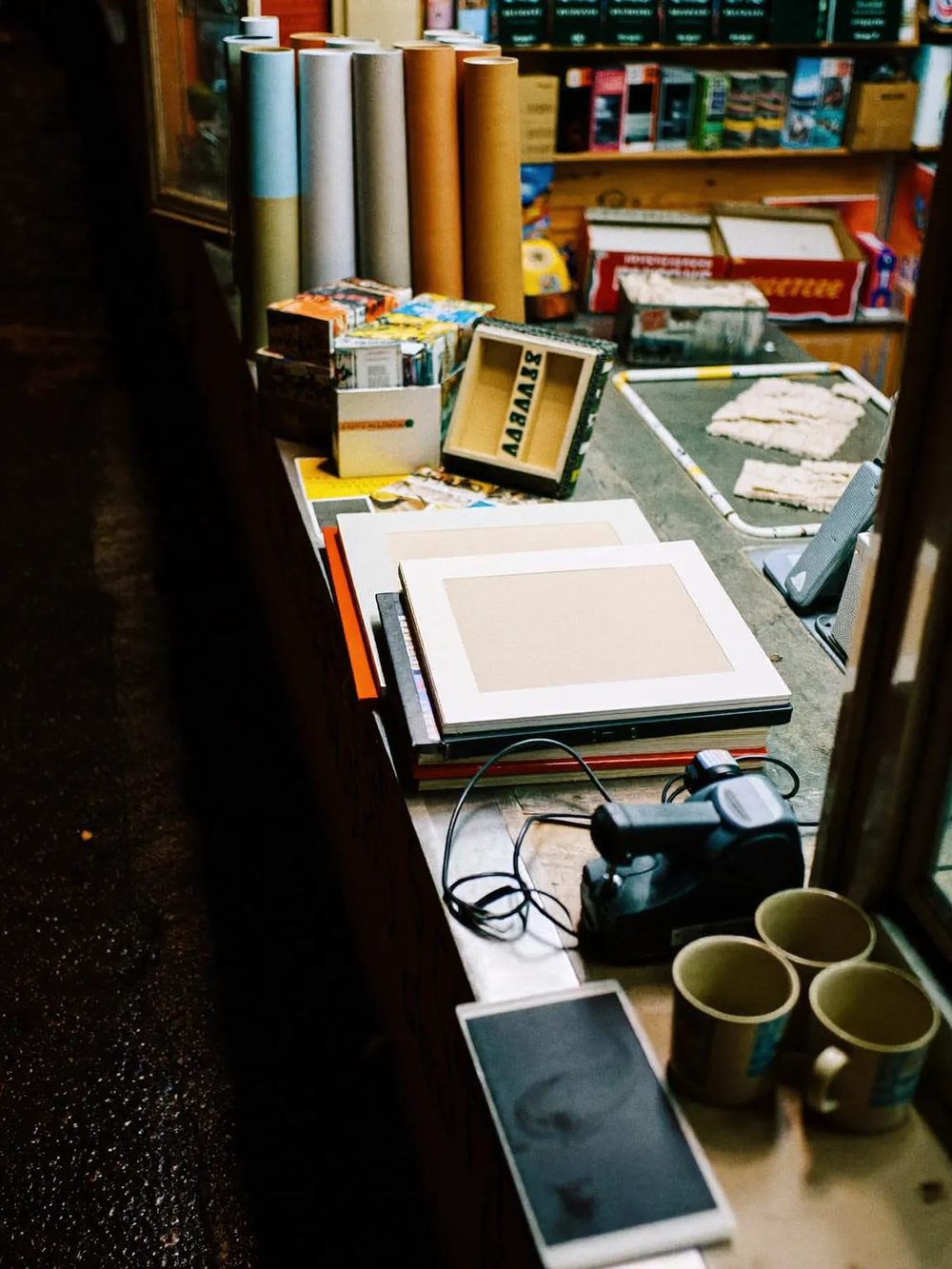 The shop counter: frames, paper rolls, blanks and cables stacked up